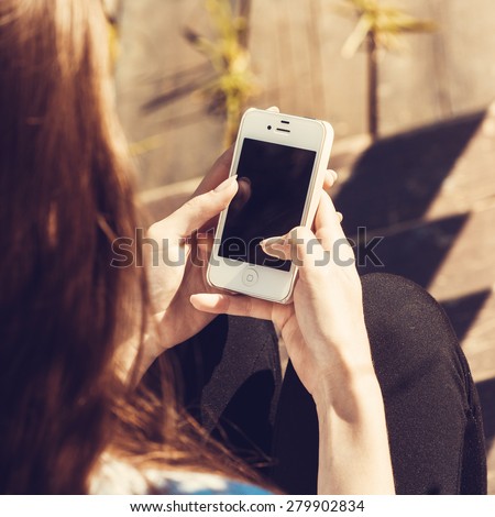 Woman using mobile smart phone in the park.