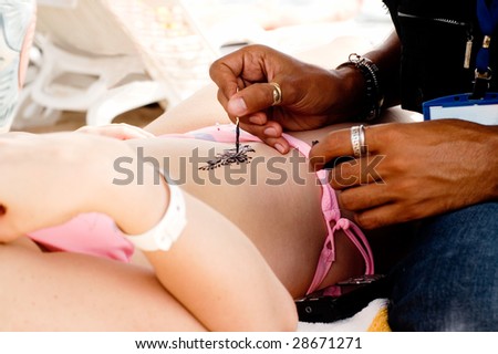 A man making temporary henna tattoo on woman\'s body