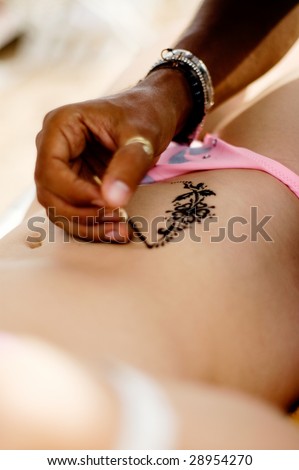 stock photo A man making temporary henna tattoo on woman's body