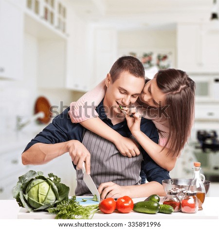happy young couple have fun in modern kitchen indoor while preparing fresh fruits and vegetables food salad.