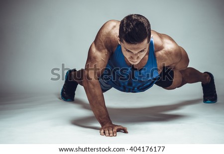 Strong young athlete doing push-ups on one hand. Sports concept.