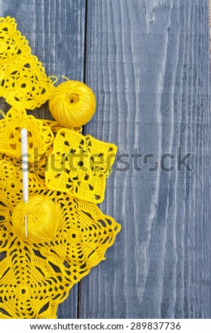 Crochet patterns on the wooden table. Yellow yarn.