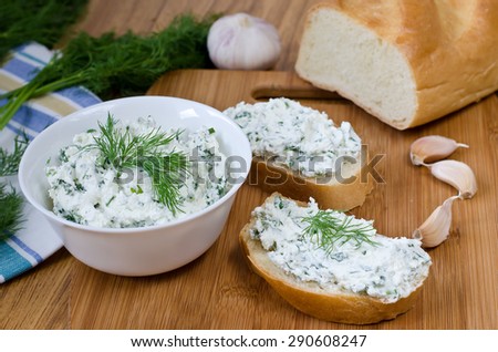 Slices of baguette with cottage cheese parsley, garlic on a cutting board. Curd sandwich in a bowl.