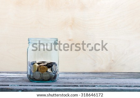 Financial concept. Coins in glass money jar. Wooden background