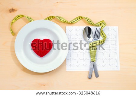 Plate with hearts, roulette, spoon and fork. Dietary food to prevent health problems