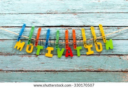 word motivation fasten clothespins on a rope behind a wooden background