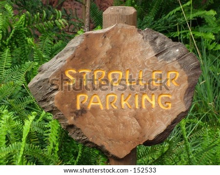 Carved wood stroller parking sign against green foliage
