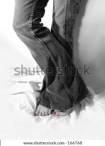 Black and white photo of young woman in jeans with bright pink toenail polish