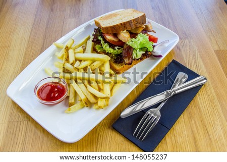 White plate with Sandwich made with bacon ,chicken and vegetables