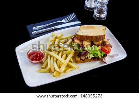 White plate with Sandwich made with bacon ,chicken and vegetables on black background