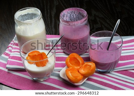 Homemade organic low fat plain, apricots and blueberry yogurt in a glass jar on colorful kitchen cloths.
