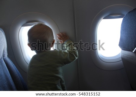 A child is looking out a window from an airplane seat.