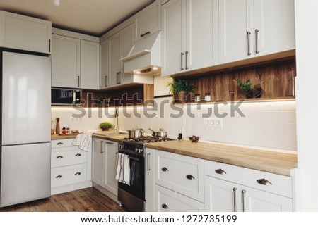 Luxury modern kitchen furniture in grey color and steel oven,fridge, sink, wooden tabletop, pots,. Gray cabinets in scandinavian style. Home renovation. Stylish kitchen interior design.