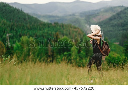 stylish hipster woman with backpack looking at  amazing woods and mountains in summer, travel concept, space for text