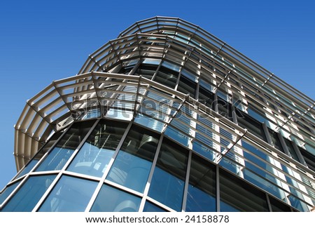 Curved high tech glass and metal office building against deep blue sky