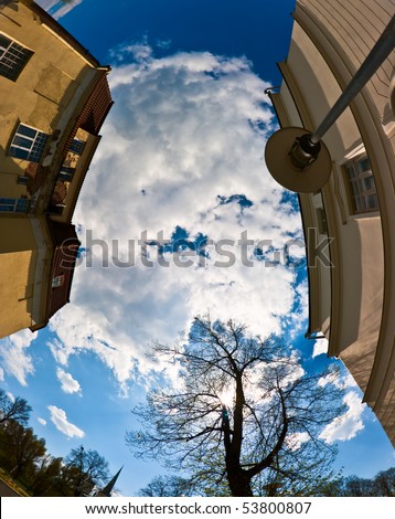 Shot with a fish-eye lens looking up to the sky of a city from below between two houses
