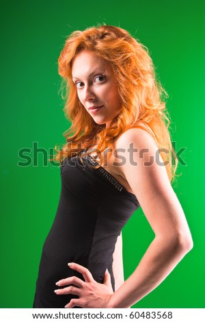 Beautiful red-haired woman with a worried look in black sarafan on a green background