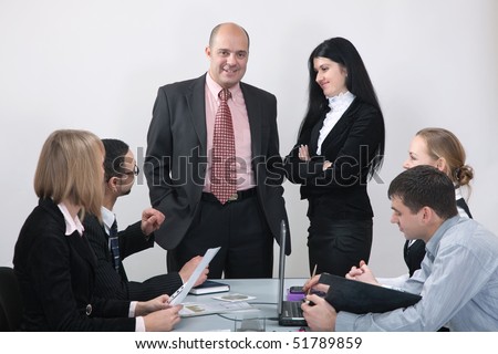 Group of business people formed of men and women working together in the office. Their leader looking at camera.