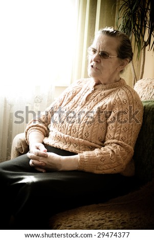 Old woman is sitting on the sofa by the window