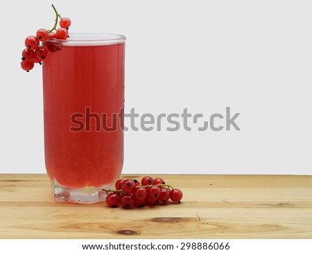 bunch of red currant and glass of fruit-drink juice on a  wood table on white background