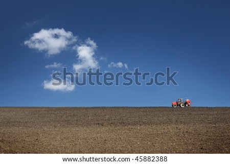 agricultural tractor cultivating on field with blue sky