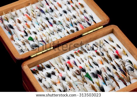 A collection of classic trout fishing flies in an old traditional wooden fly box