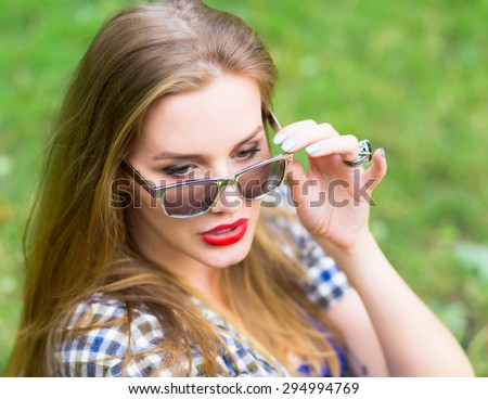 Close up summer fashion portrait of beautiful young sexy woman posing in city park, wearing hipster sunglasses, have natural amazing long blond hair, red attractive lips and perfect skin.