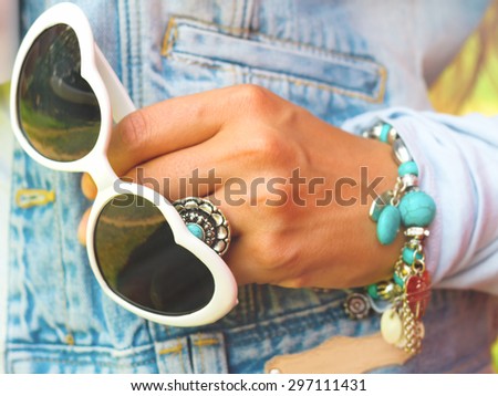 Young stylish woman in jeans vest  with white heart shaped sunglasses, retro bracelet with turquoise stone, retro ring with turquoise blue stone,summer  fashion concept in sunny day