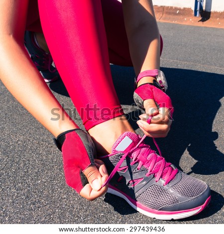 Running shoes-closeup woman tying shoe laces. Female sport fitness runner getting ready for jogging outdoors on forest path in spring or summer. Street runner getting ready for training. Pink leggins.