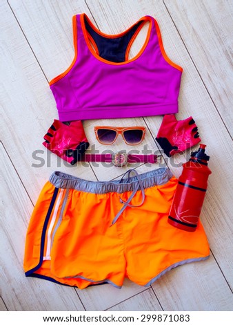 Gym outfit-workout clothing while working out at the fitness center. Matching clothes, sports bra, shorts in pink and orange. Sport equipment.set for sports activities,water bottle.Fitness concept