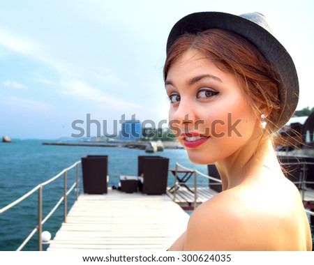 Summer close up fashion portrait of young hipster girl,positive surprised emotions,smile,on the amazing city sea view terrace.Odessa.Travel tourism and people concept. in marina against yachts in port