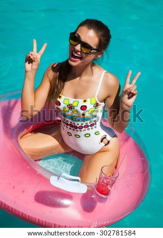 Beautiful sexy young woman with perfect slim figure with long dark hair and wet bathing suit fashion in stylish glasses from the sun is sunning by swimming pool swim, sunbathe have fun at beach party
