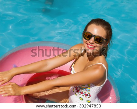 beautiful long hair female model posing by the pool, outdoor portrait.wet bathing suit fashion in stylish glasses from the sun is sunning by swimming pool swim, sunbathe have fun at pool party