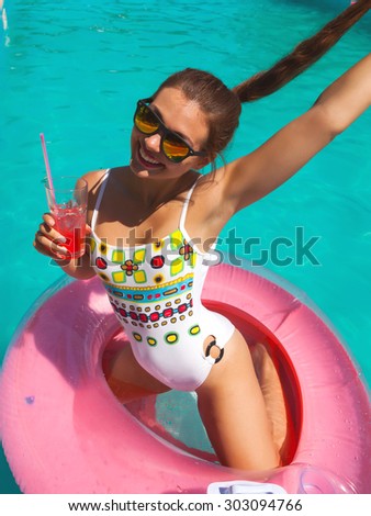 Sexy woman in bikini enjoying summer sun and tanning during holidays in pool with cocktail. Top view. Woman in swimming pool. Sexy woman in bikini.Pink pool circle.Joy,positive,vacation.Going crazy
