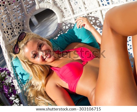 Beautiful woman in bikini  in the beach club.Outdoor fashion portrait of glamour lady enjoying her vacation on luxury villa, wearing stylish sunglasses and navy bikini. nice summer day.