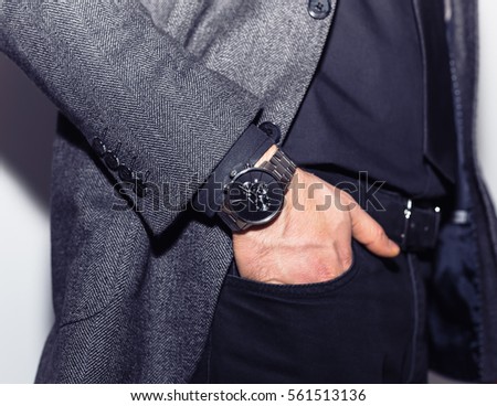 closeup fashion image luxury watch on wrist of man.body detail of a business man.Man\'s hand in a white shirt with cufflinks in a pants pocket closeup and black vest at white background.Not isolated