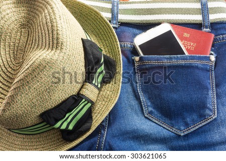 Passort and mobile phone in the pocket of blue jeans and a straw hat with bow, a man goes on a big journey