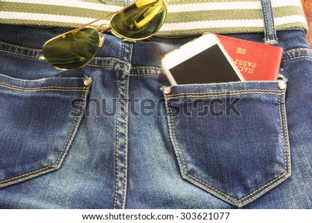 Passort and mobile phone in the pocket of blue jeans and sunglasses, a man goes on a big journey