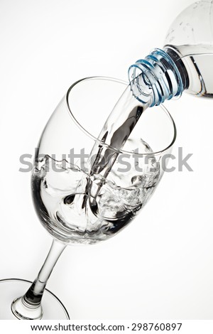 Pouring water from bottle to the glass isolated on white background