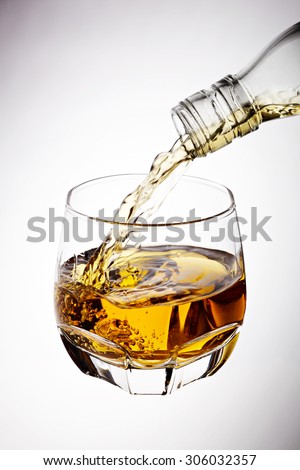 Whisky pouring in glass isolated on white background