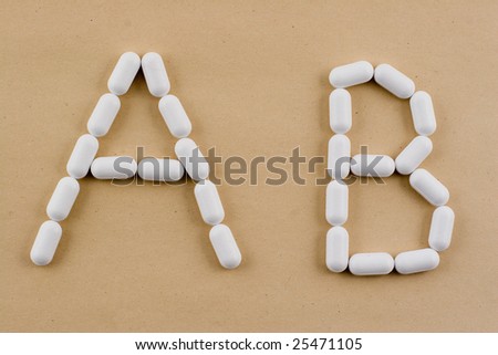 A and B letters laid out with medical pills on a brown paper background