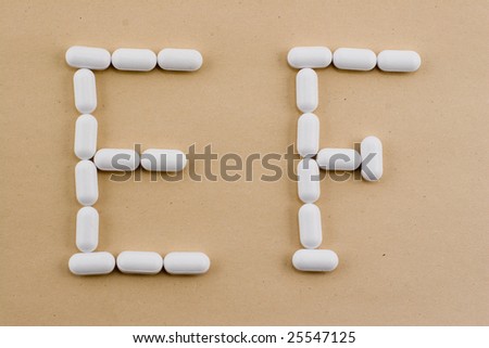 E and F letters laid out with medical pills on a brown paper background
