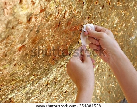 sticking the gold leaf by hands on the wall rock,  for respecting the Buddha