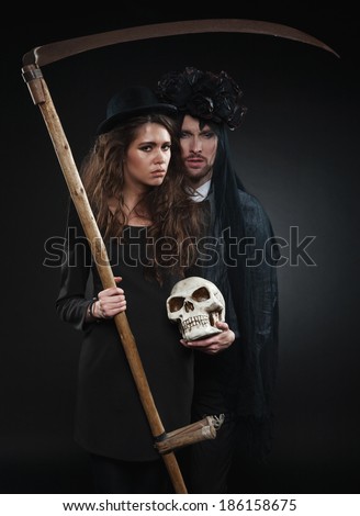 Classic vintage woman poses with black roses and her husband in makeup for All Souls Day
