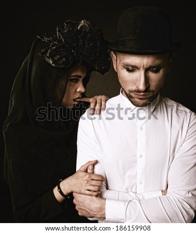 Classic vintage woman poses with black roses and her husband in makeup for All Souls Day