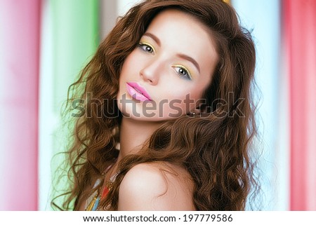 Portrait of young beautiful girl with long hair with color makeup on bright colored background.