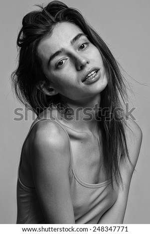 Portrait of beautiful fashion model posing over gray background. Black and white studio shot