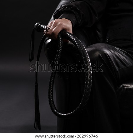 male hand holding black leather whip
