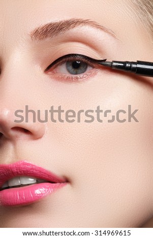 Beautiful woman with bright make up eye with sexy black liner makeup. Fashion arrow shape. Chic evening make-up. Makeup beauty with brush eye liner on pretty woman face