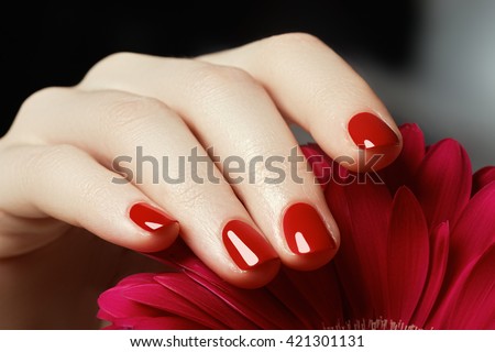 Beauty delicate hands with manicure holding pink flower  close up. Beautiful nails and flower close-up, great idea for the advertising of cosmetics.